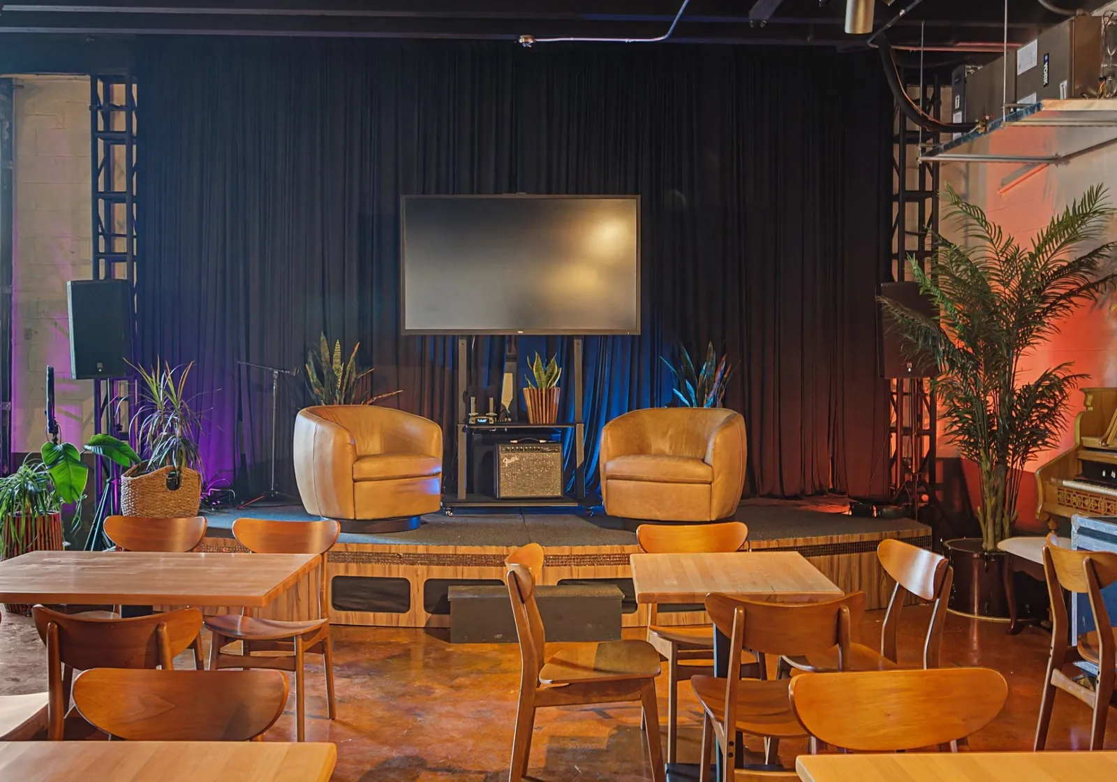 Stage with TV and lounge chairs in the main event space at Music City Work Club in The Nations, Nashville